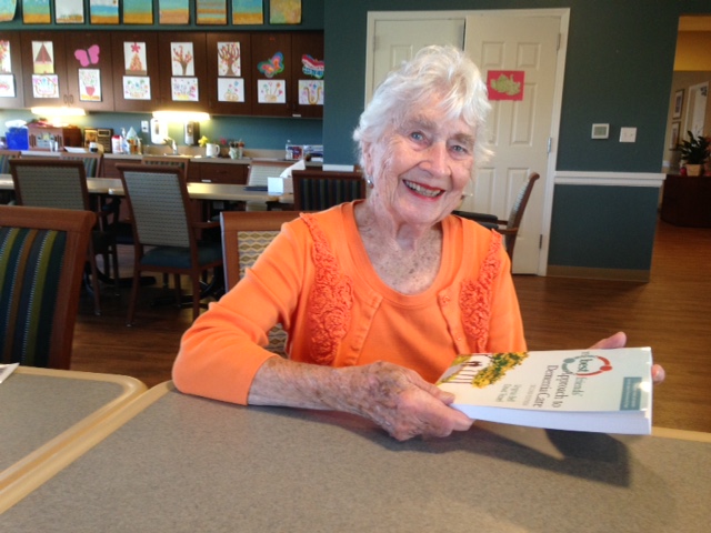 Virginia Bell posing with The Best Friends Approach to Dementia Care book